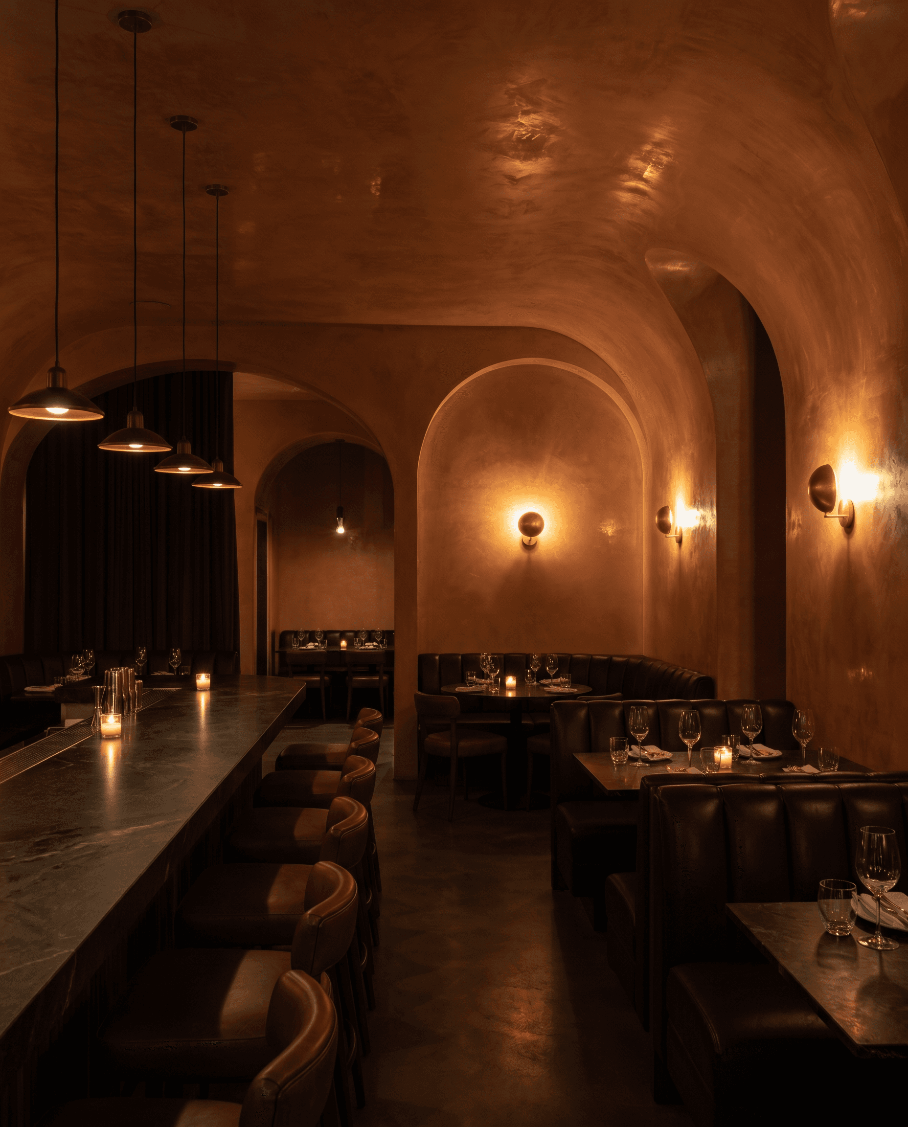 Upscale restaurant and bar with curved archways finished in rich terracotta-stone Venetian Marmorino plaster and warm ambient lighting